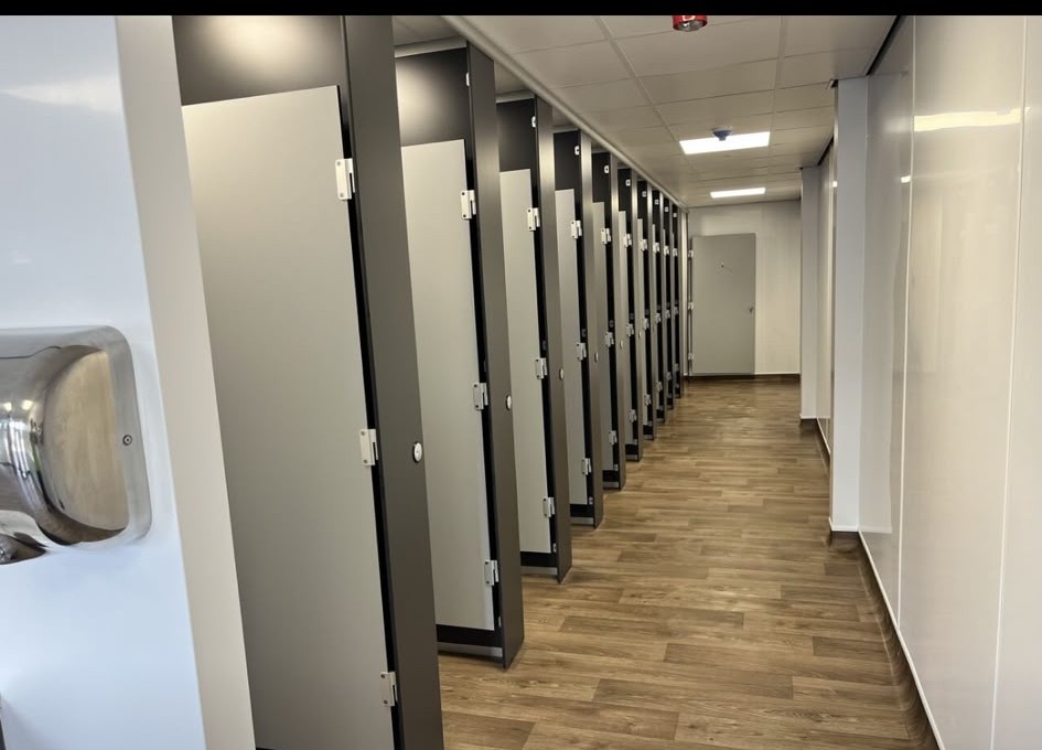 Corridor of washroom cubicles with wood-effect flooring