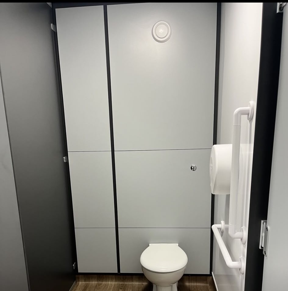 Accessible toilet cubicle with grab rails and panelling